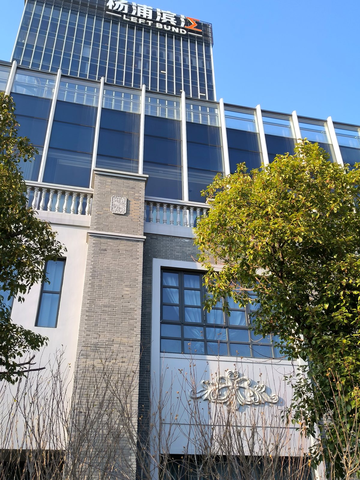 杨浦滨江一栋上部玻璃塔楼下部红砖老楼的复合建筑，顶部有杨浦滨江LEFT BUND标识